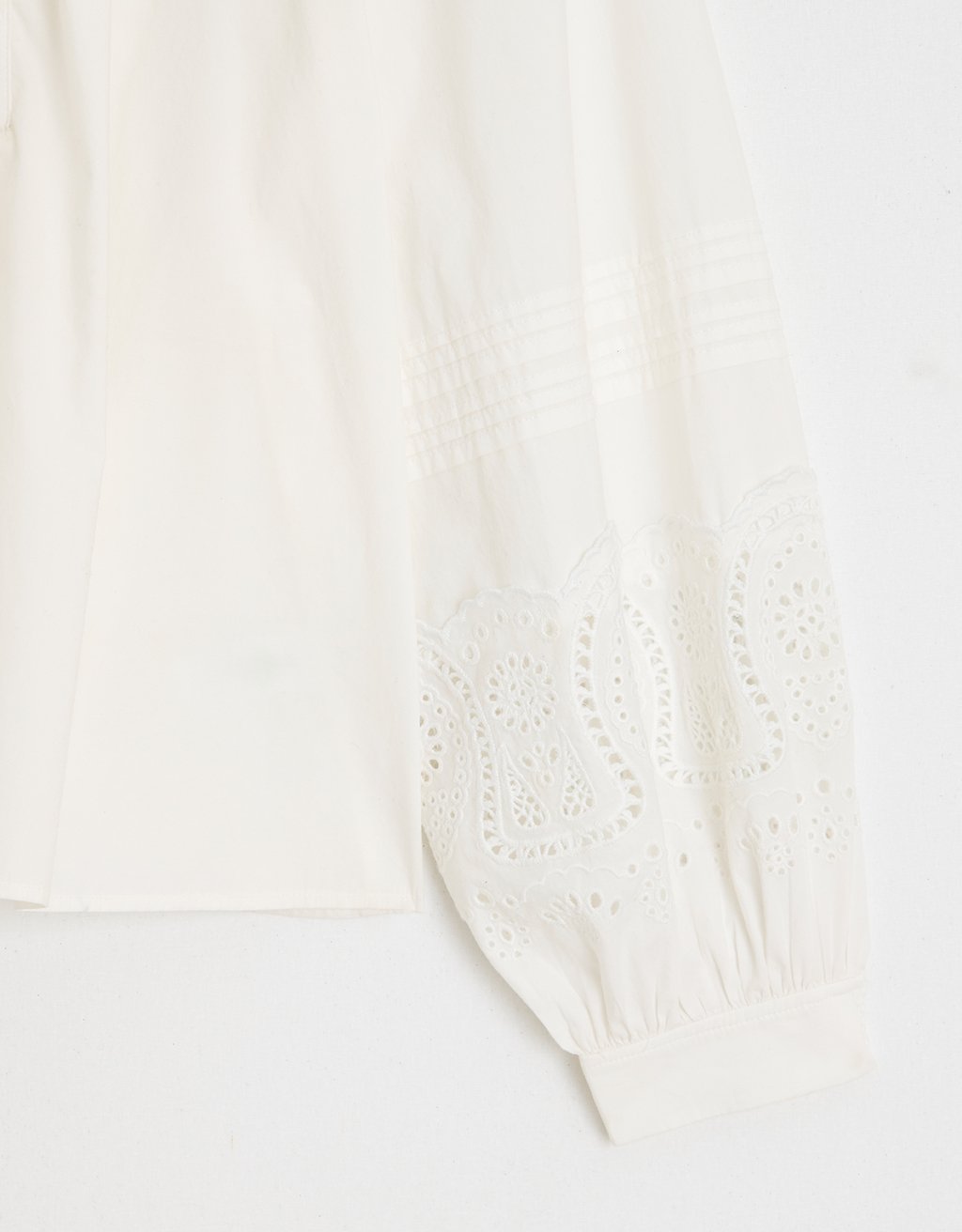 Close-up of a white fabric with embroidery detailing on a light background
