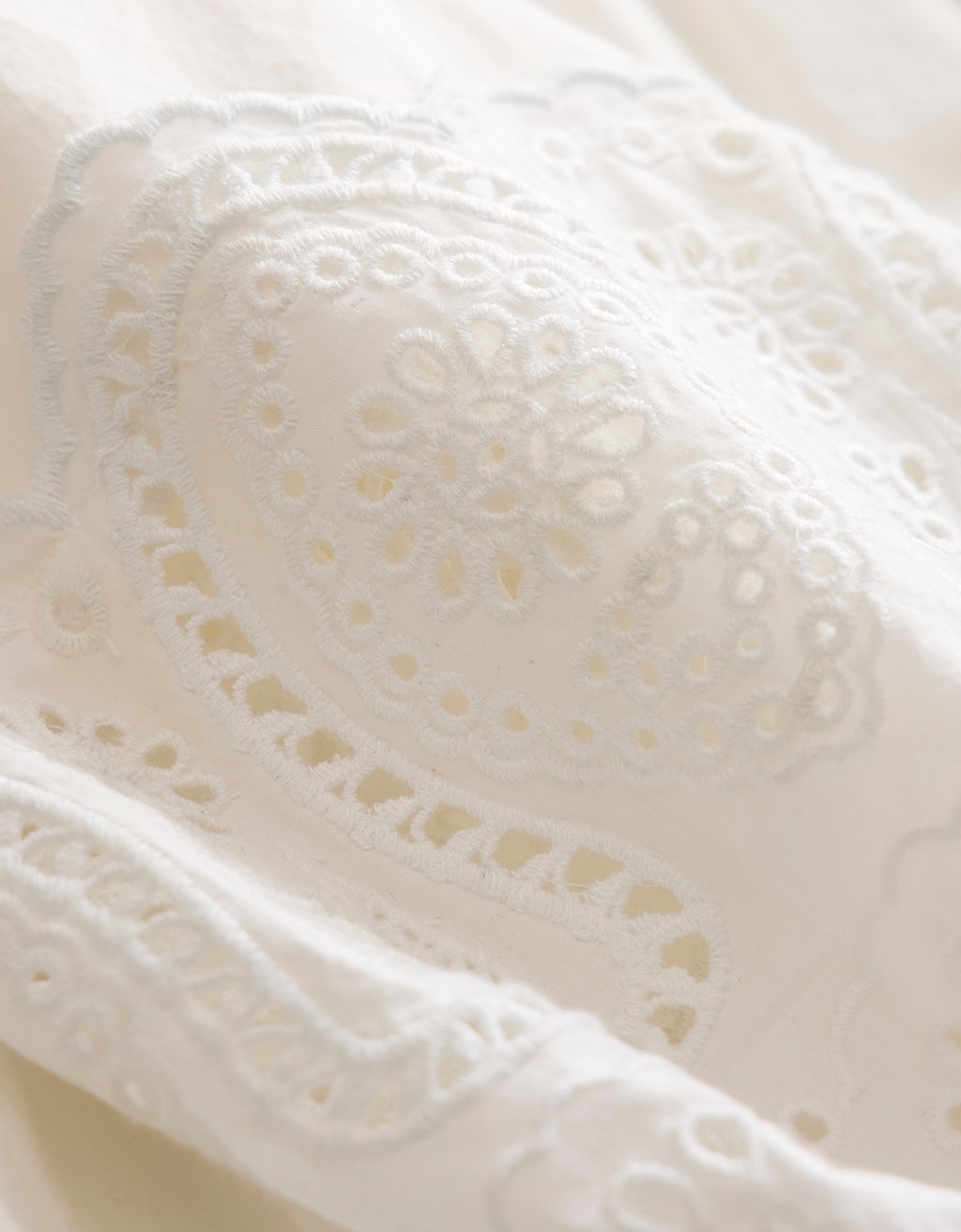 Close-up of white poplin fabric with intricate embroidery detailing