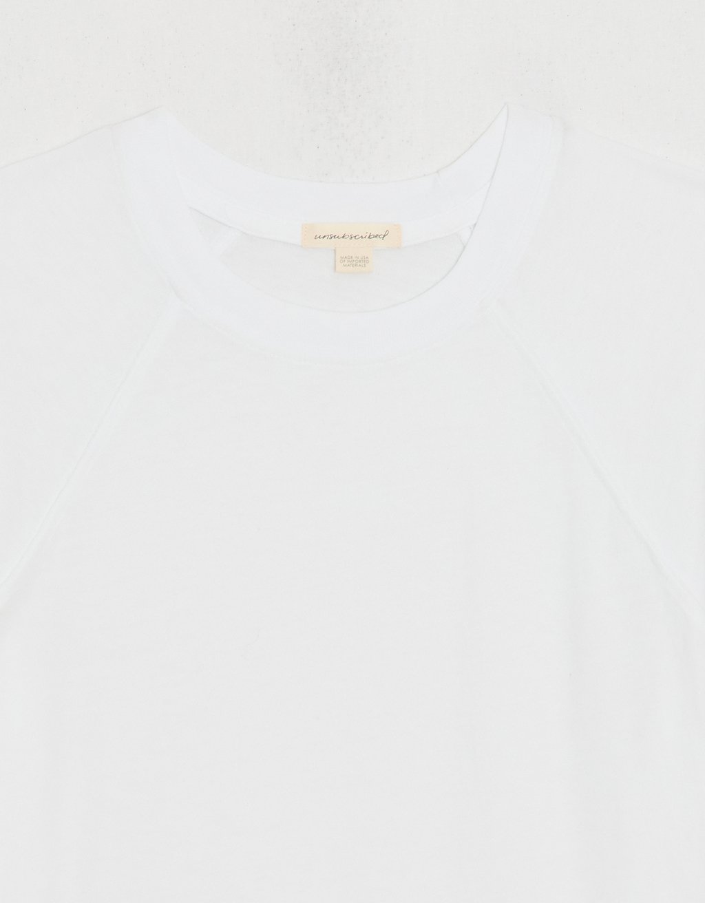 Close-up of a white t-shirt with exposed unsubscribed brand tag on a white background