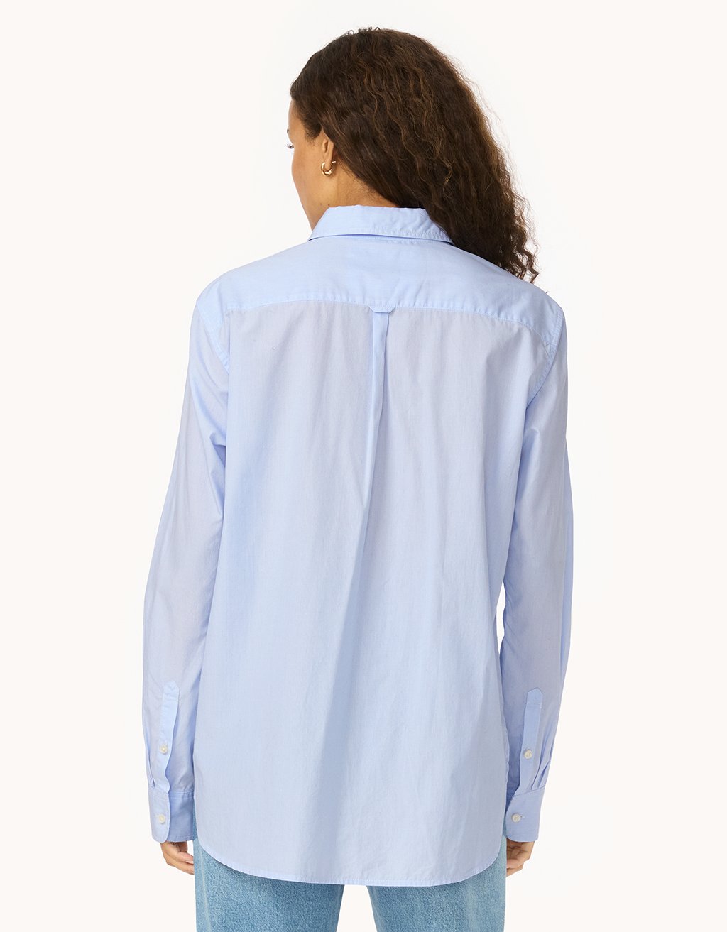 Back view of a person wearing a light blue shirt and jeans on a white background