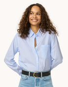 Woman wearing a light blue button down shirt and jeans on a white background