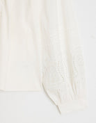 Close-up of a white fabric with embroidery detailing on a light background