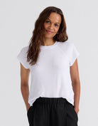 Woman wearing a white raglan t-shirt and gray pants on a white background