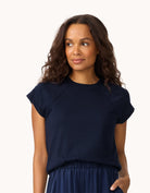Woman wearing a navy blue raglan t-shirt and skirt on a white background