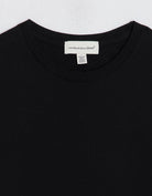 Close-up of a black t-shirt with an unsubscribed brand label on a light gray background