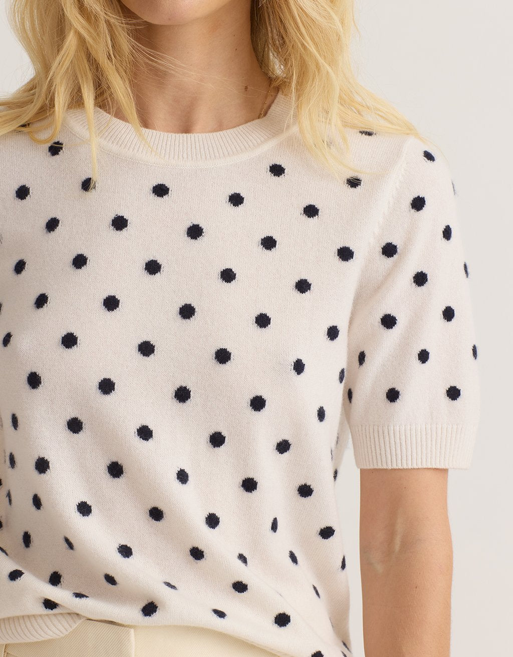 Close-up of a cream cashmere tee with polka dots worn by a person