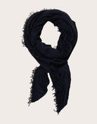Navy blue cashmere scarf with frayed edges on a light background