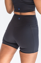 A close up shot of the back of a woman's body as she walks away. She is wearing a black workout set with the focus on the biker shorts.